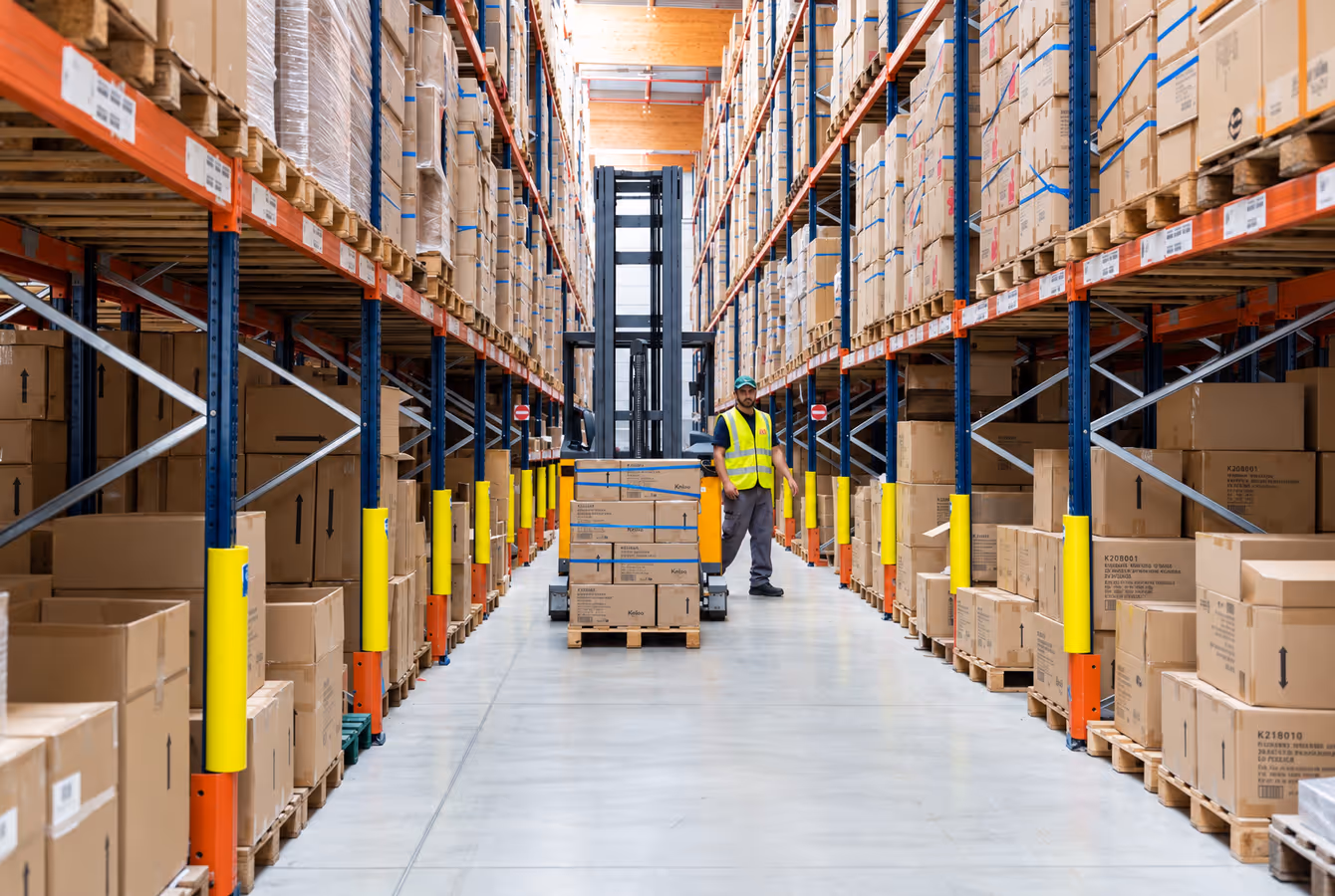 Cariste au fond d'une allée de stockage racké, cartons palettisés de part et d'autre