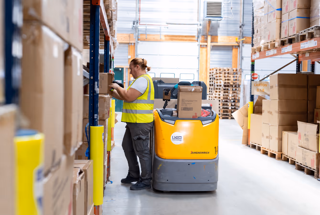 Préparateur sur chariot électrique prélevant un carton en rack