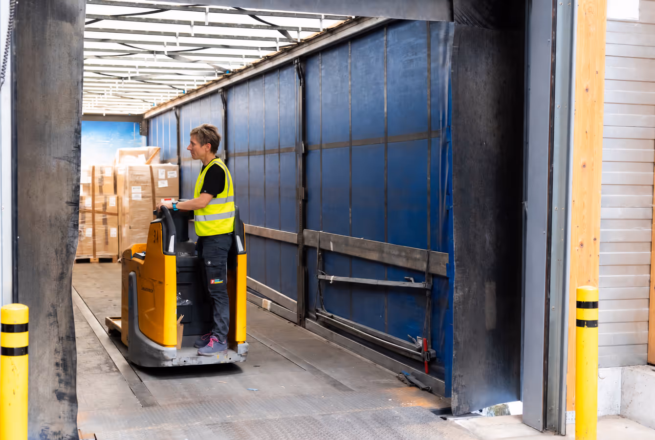 Chariot électrique chargeant des palettes dans une remorque à quai