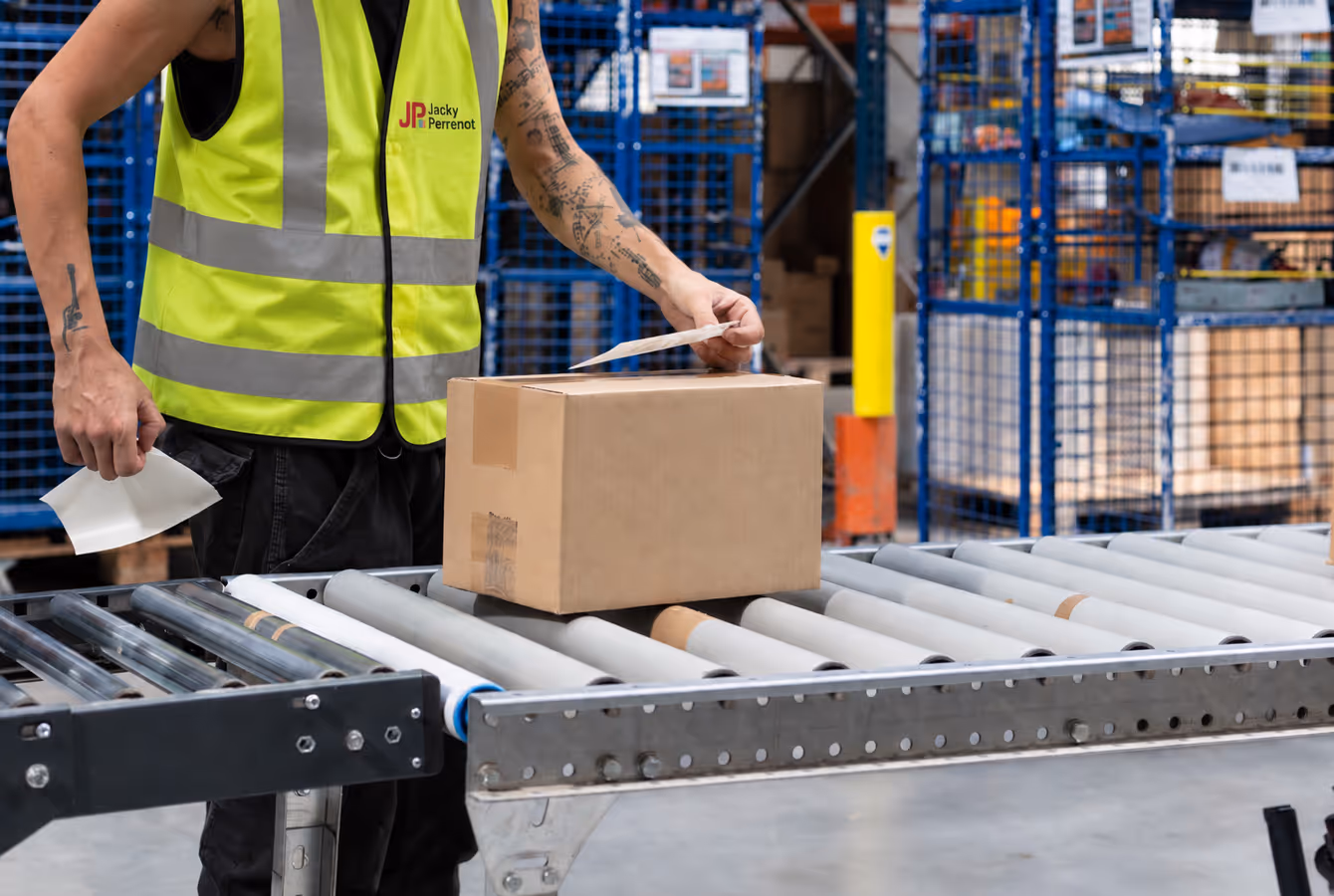 Préparateur posant un carton sur un convoyeur à rouleaux
