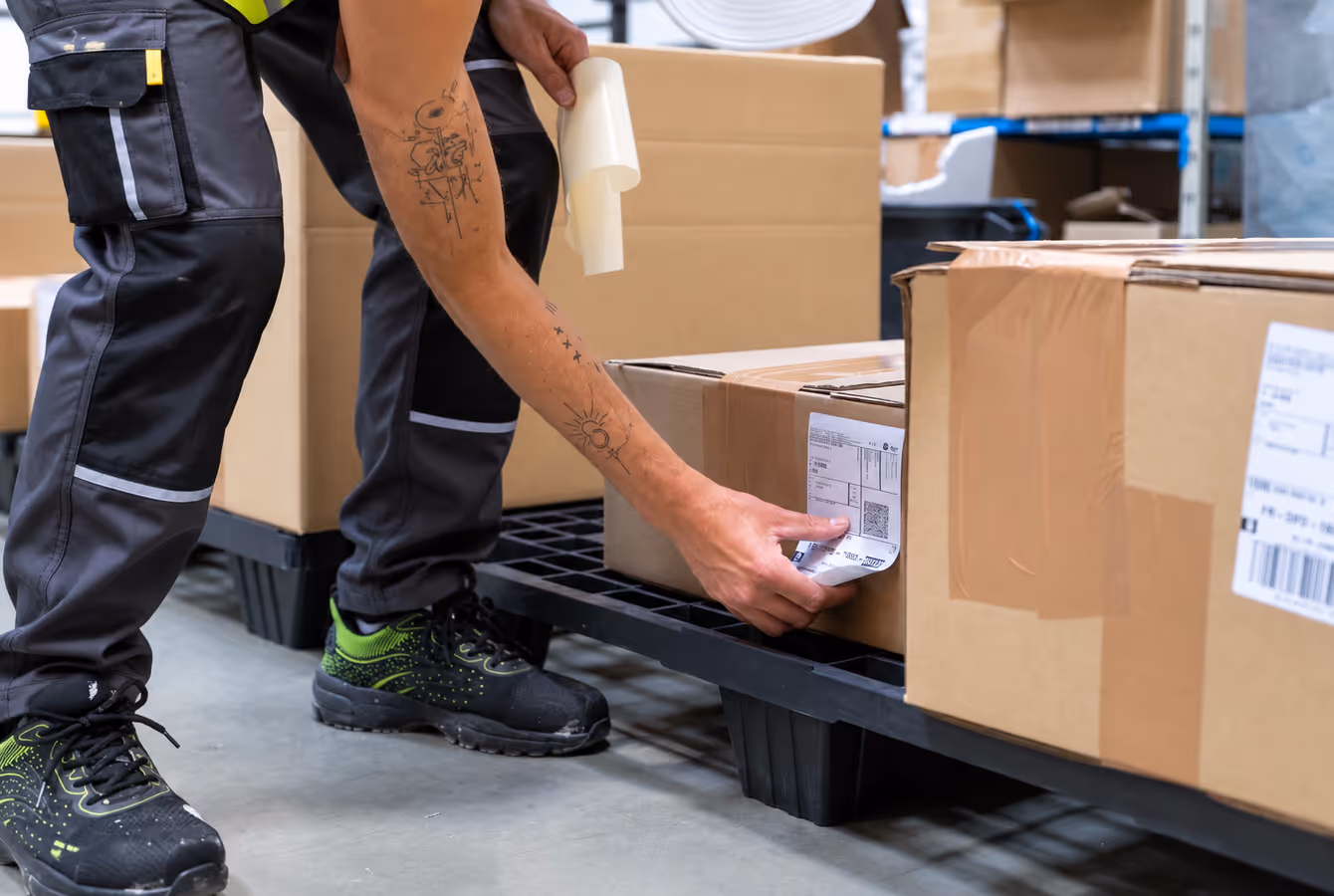 Opérateur collant une étiquette d'expédition sur un carton