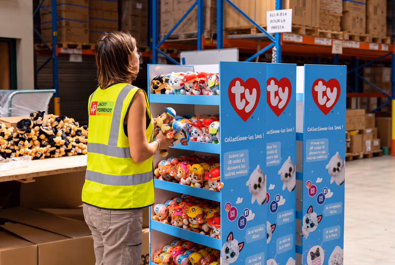 Opératrice garnissant un présentoir Ty en carton de peluches