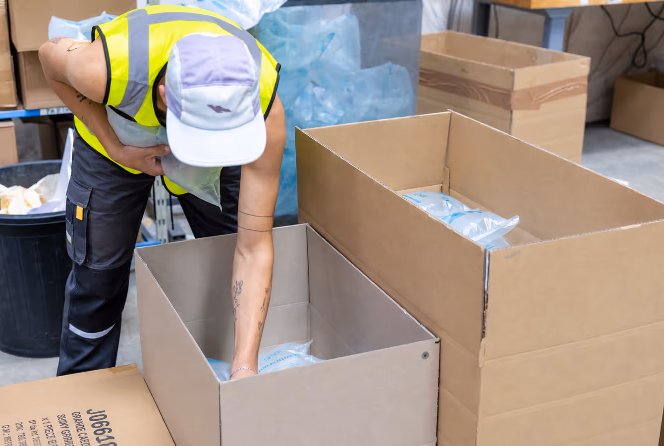 Opérateur remplissant un grand carton de produits emballés