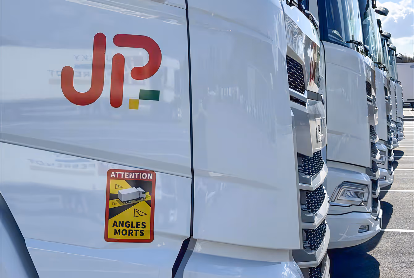 Cabines de camions Jacky Perrenot alignées, logo JP sur la portière